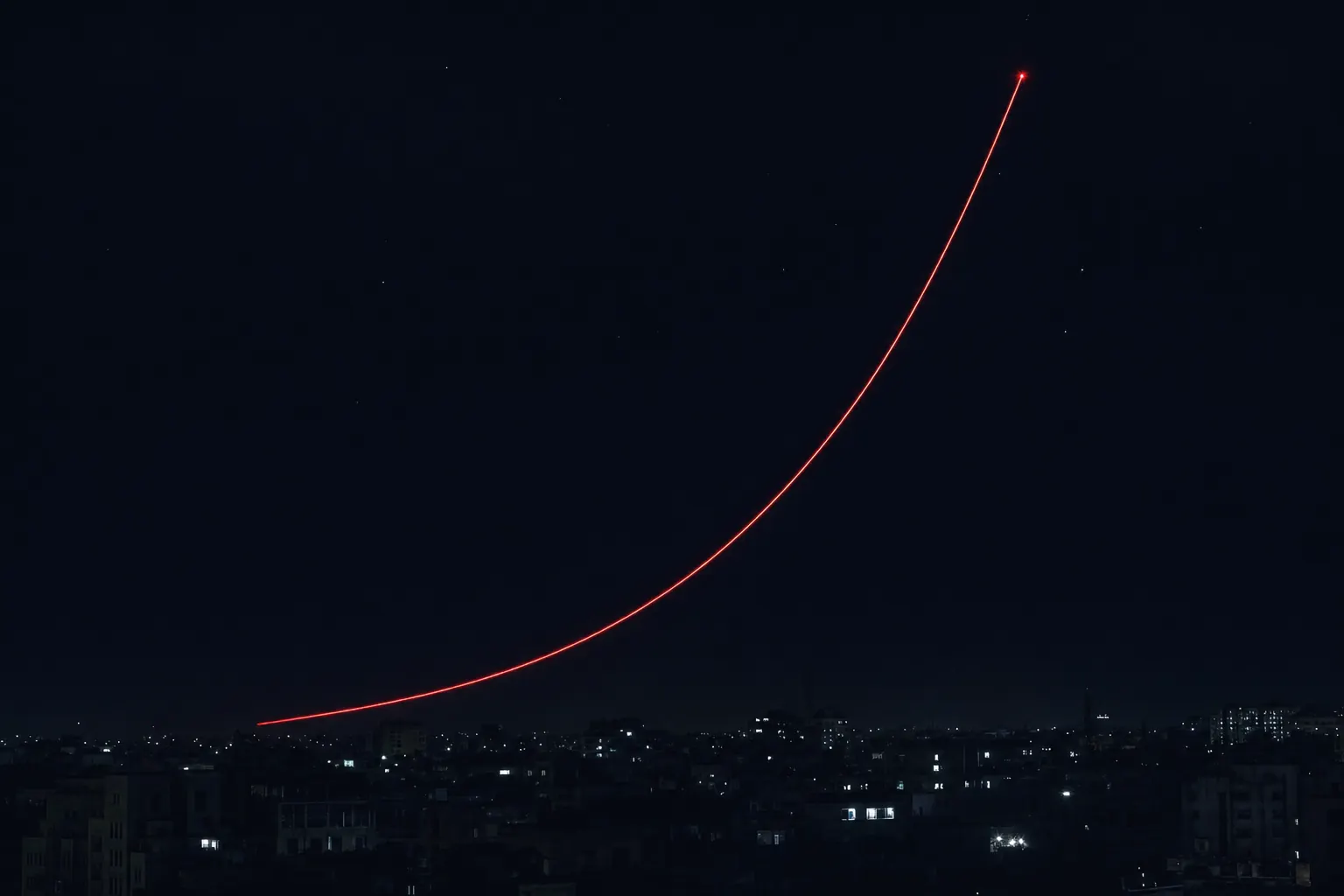 Gece şehrinin üstünde sol alttan sağ üste yükselen kırmızı kalkış izi